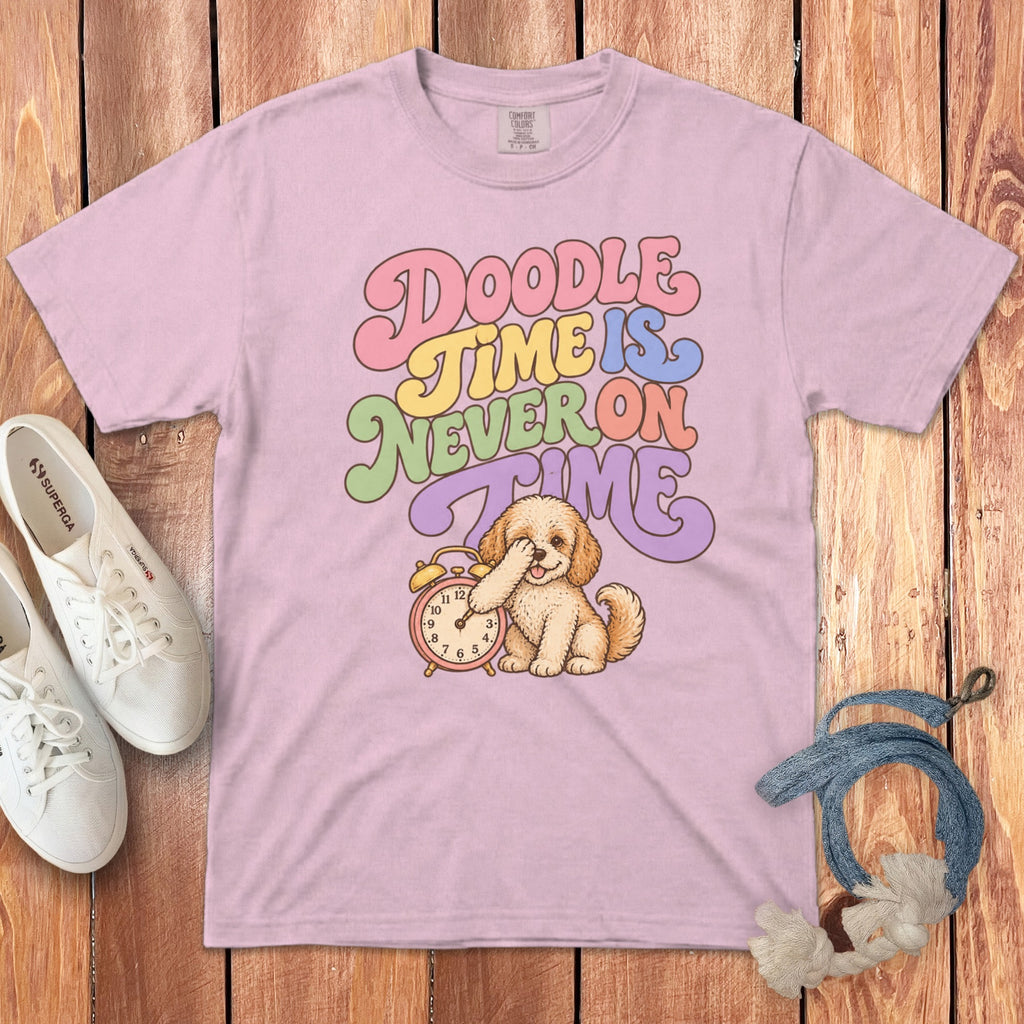 A light pink t-shirt featuring the colorful text Doodle Time is Never on Time and an illustration of a doodle puppy holding a red alarm clock.