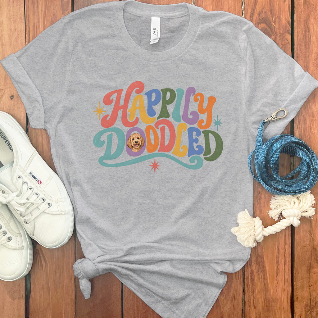 Grey t-shirt with "Happily Doodled" in colorful retro font and a dog's face.