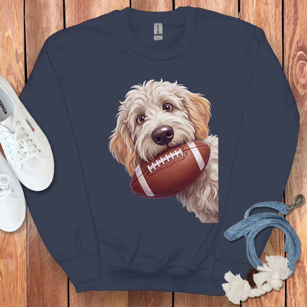 Fluffy dog holding football on navy blue sweatshirt.