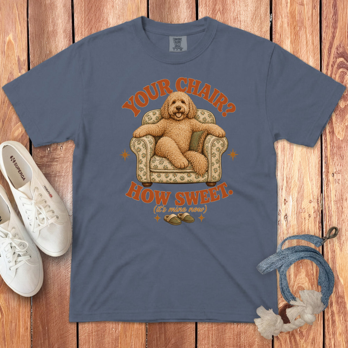 Blue t-shirt featuring a graphic of a golden doodle relaxing in a floral armchair with the text YOUR CHAIR? HOW SWEET.