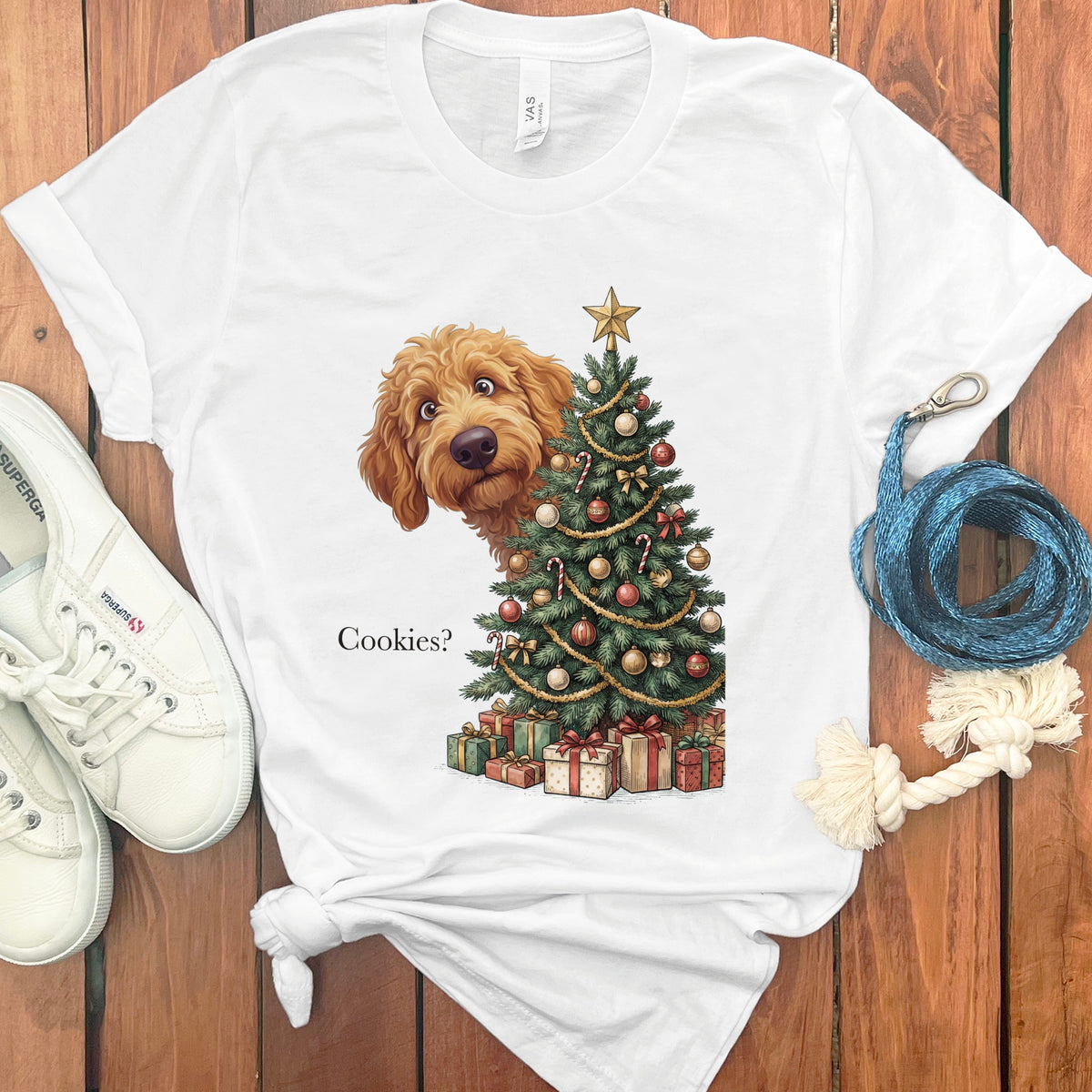 A golden doodle peeks from behind a decorated Christmas tree with gifts and text that reads "Cookies?".