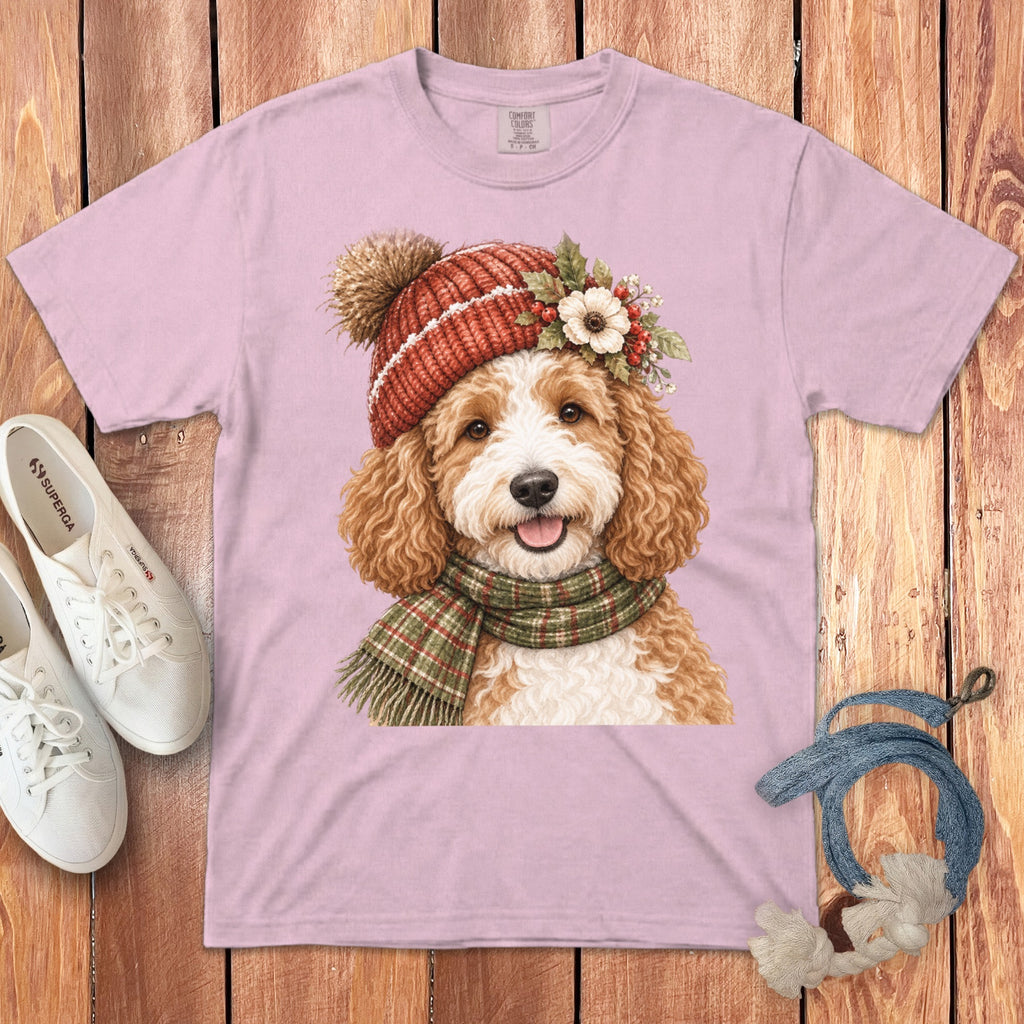 Pink t-shirt with a watercolor print of a fluffy dog wearing a winter hat and scarf.
