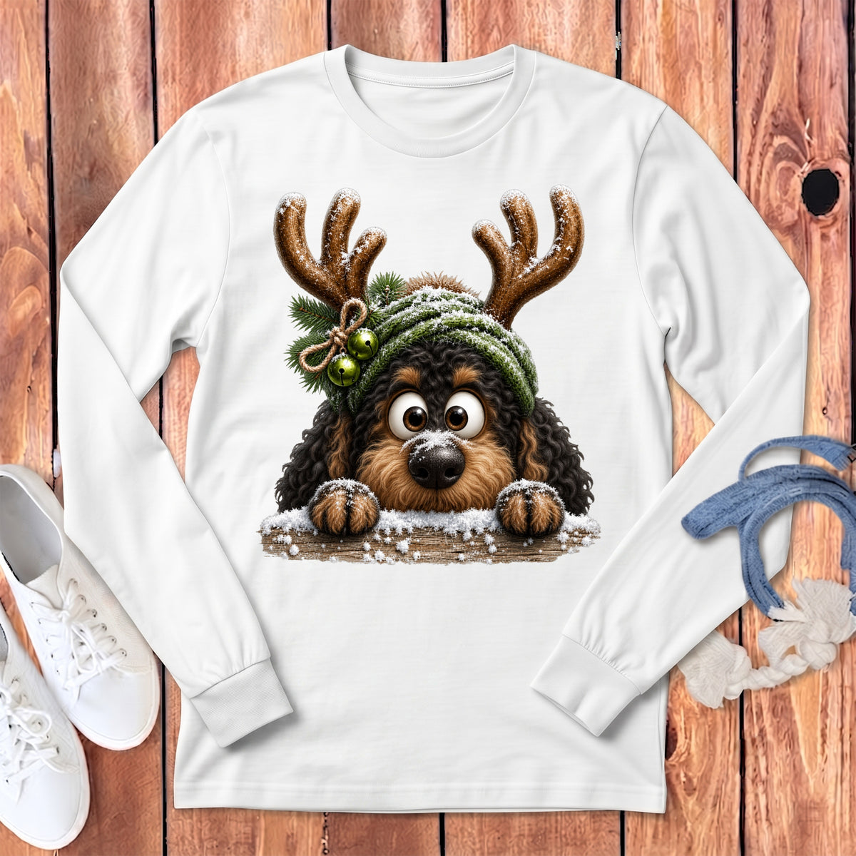 Cute cartoon dog with reindeer antlers and festive hat on a white long-sleeve shirt.
