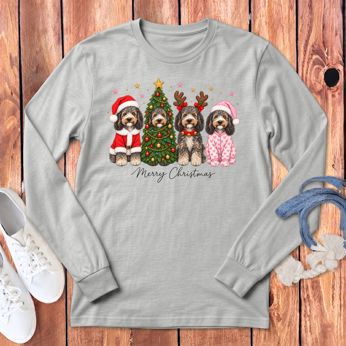 A gray long-sleeve t-shirt features a graphic of four doodle dogs celebrating Christmas alongside a decorated tree.