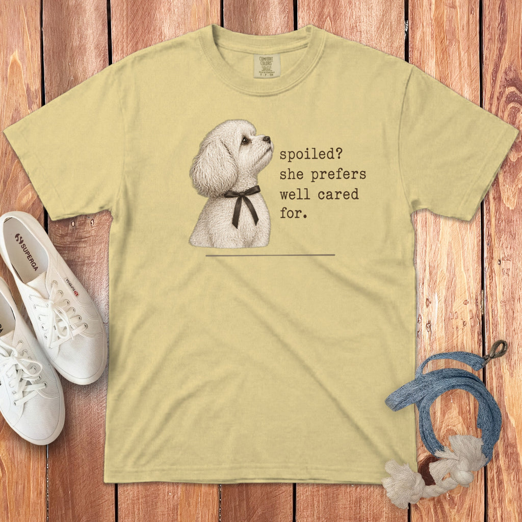 Pale yellow t-shirt featuring a white poodle illustration and text reading spoiled? she prefers well cared for.