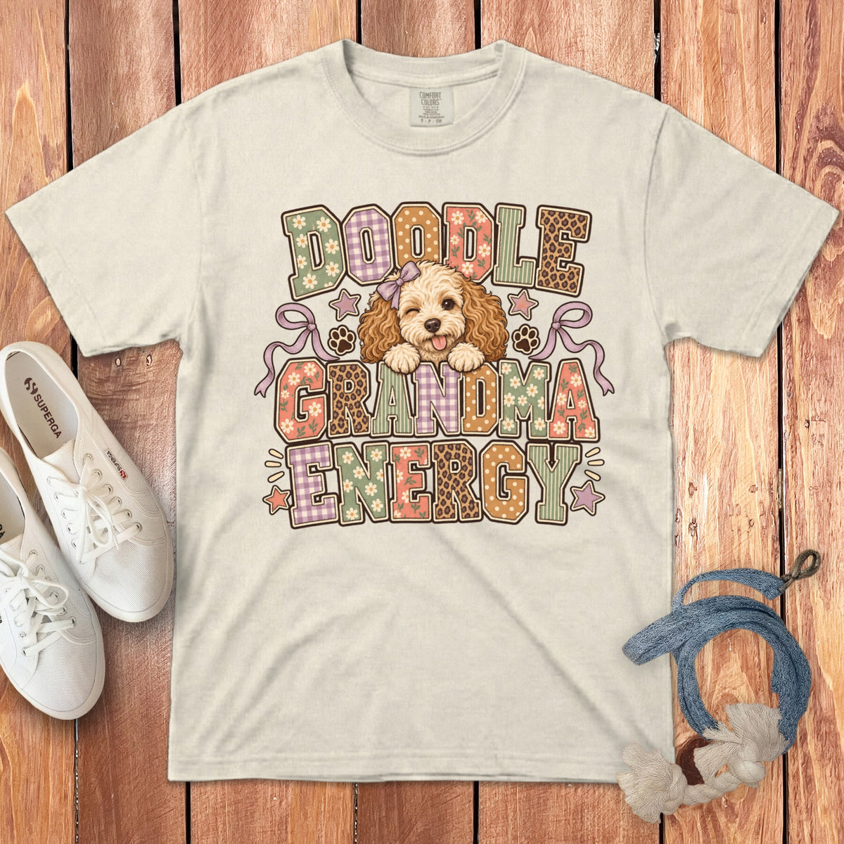 Off-white t-shirt with Doodle Grandma Energy graphic, featuring a cartoon poodle, paw prints, and patterned letters.