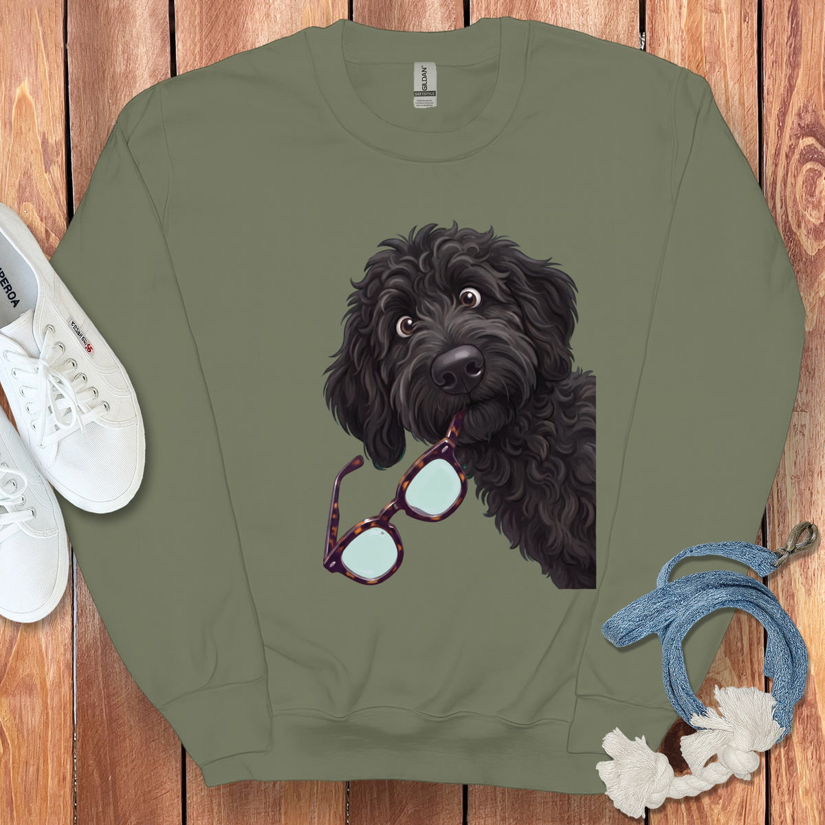 An olive green crewneck sweatshirt featuring an illustration of a black doodle dog holding glasses.