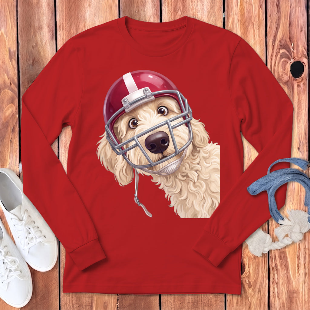 Golden doodle puppy wearing a red football helmet on a red long-sleeve shirt.