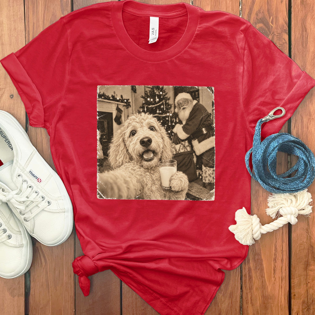 A red crewneck t-shirt featuring a vintage graphic of a fluffy dog holding a glass of milk with Santa Claus in the background.
