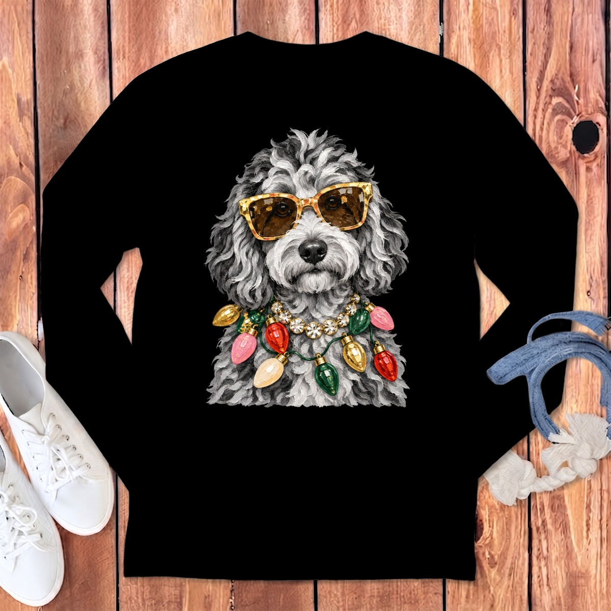 Dog wearing sunglasses and a Christmas light necklace on a black long-sleeve shirt.