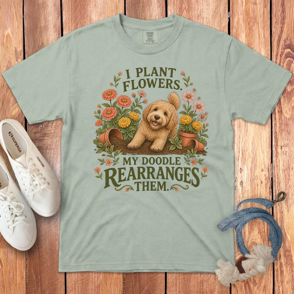 Sage green t-shirt featuring a goldendoodle graphic and text reading I plant flowers my doodle rearranges them.