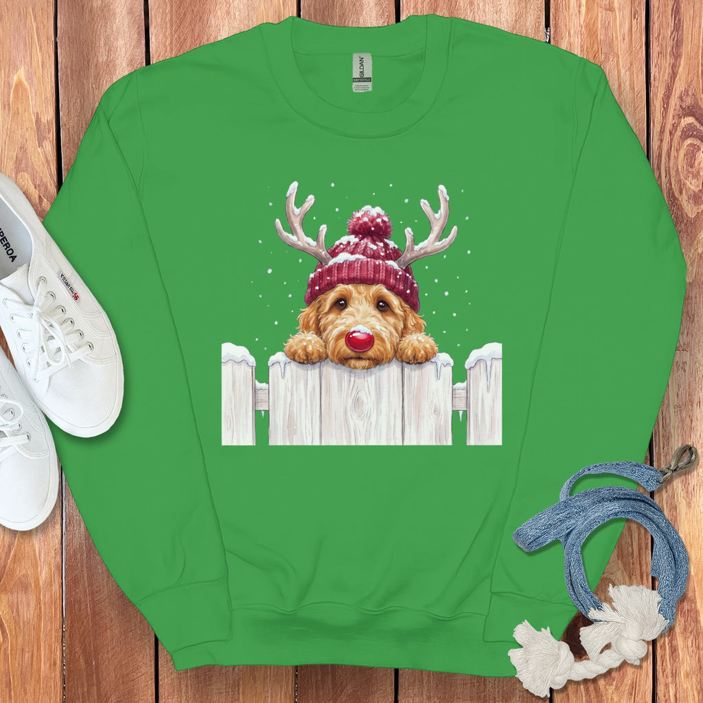 Green sweatshirt with a dog wearing a reindeer hat over a white picket fence.