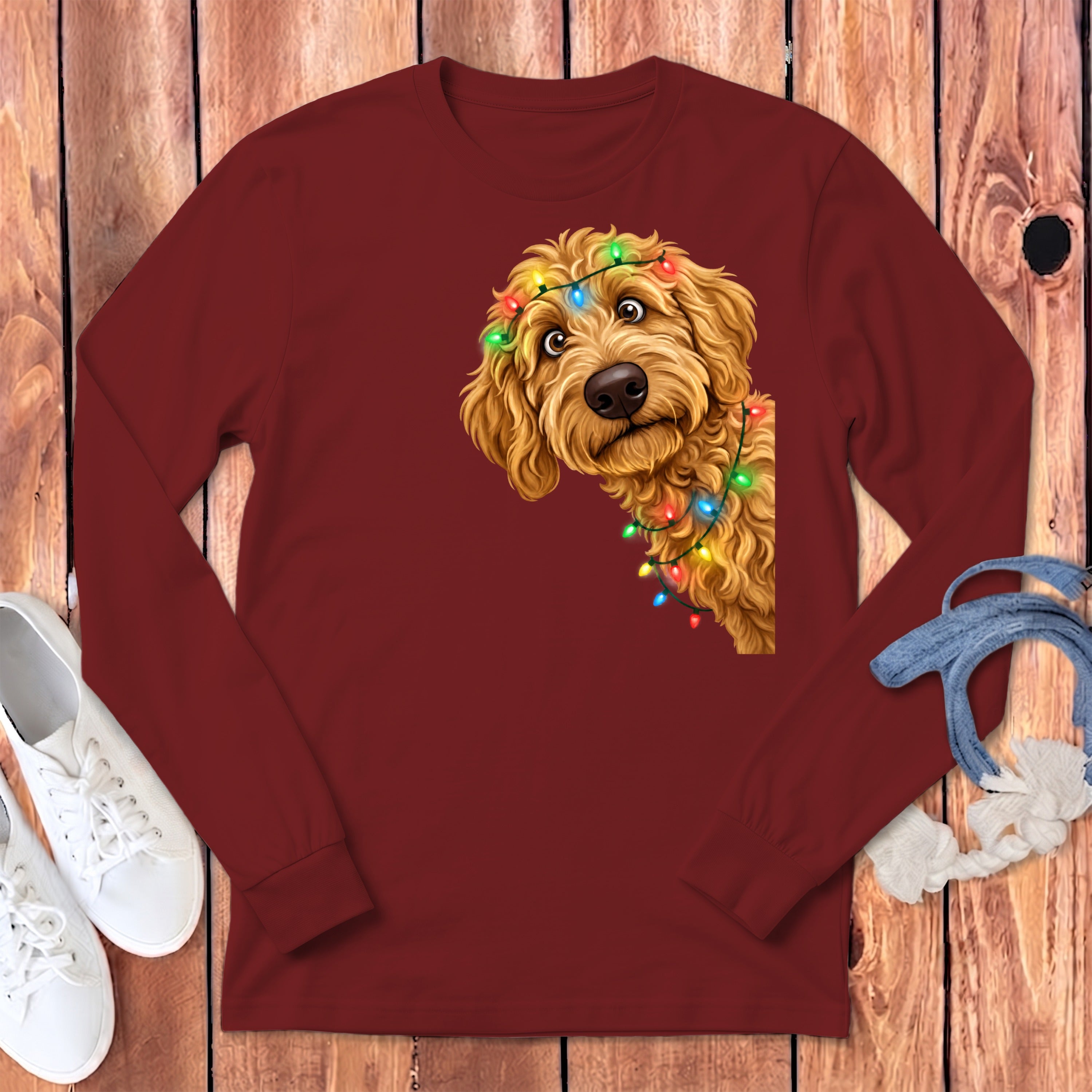 Goldendoodle puppy with colorful Christmas lights on a maroon long-sleeve shirt.
