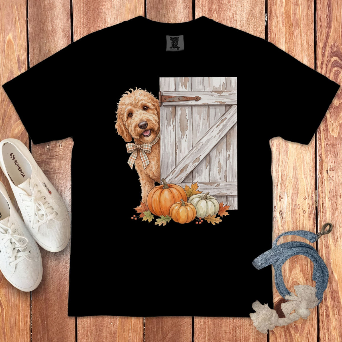 Black t-shirt with a dog peeking from behind a rustic door and pumpkins.