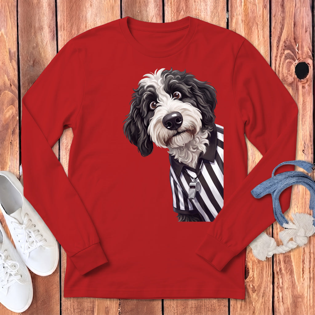 Black and white dog wearing a referee shirt with a whistle on red long sleeve shirt