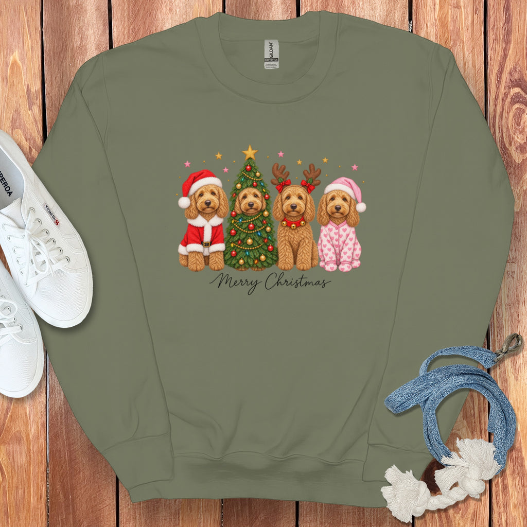 An olive green crewneck sweatshirt featuring a graphic of four doodle dogs in Christmas costumes and pajamas surrounding a decorated tree.
