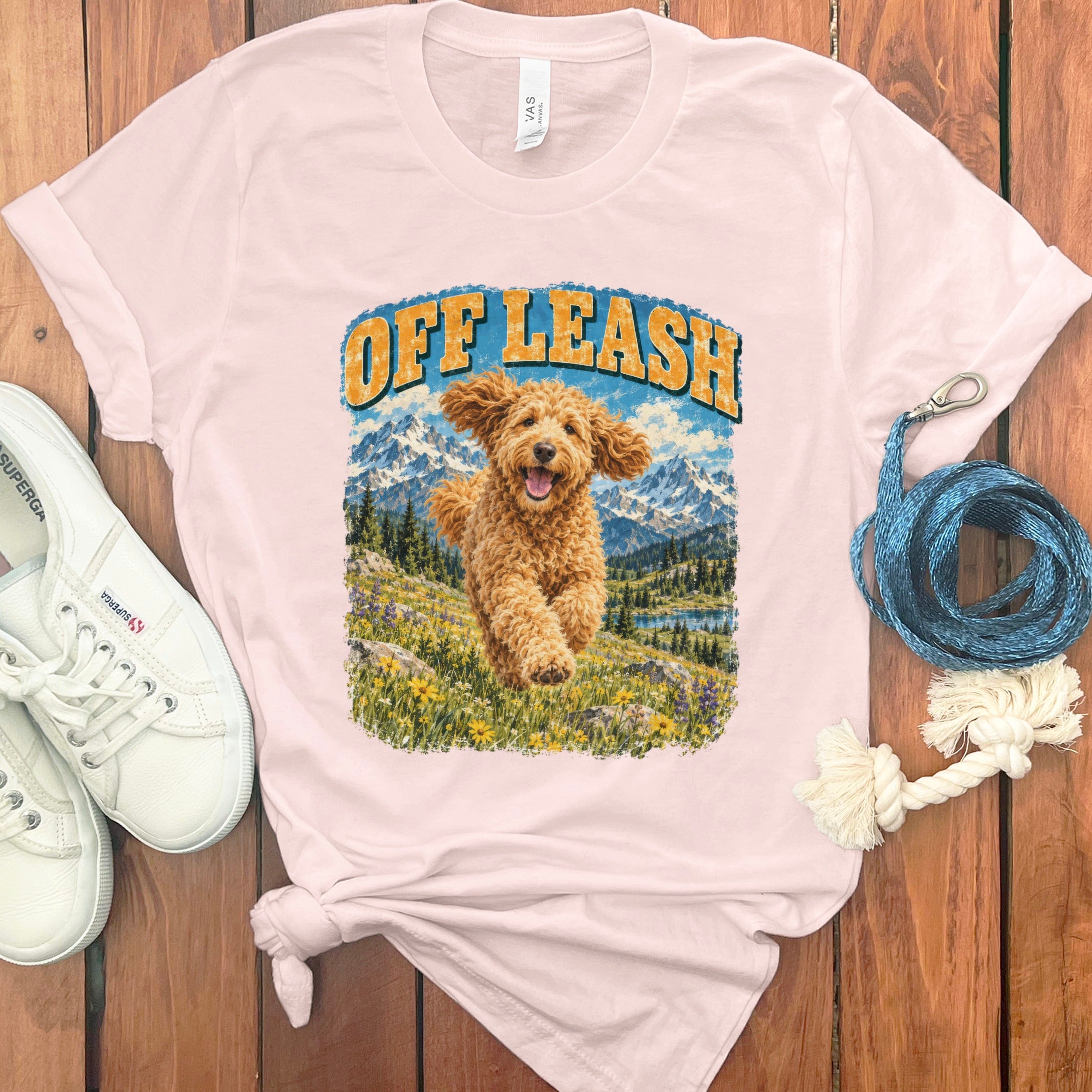 T-shirt with a running golden doodle, mountains, lake, and text "OFF LEASH".
