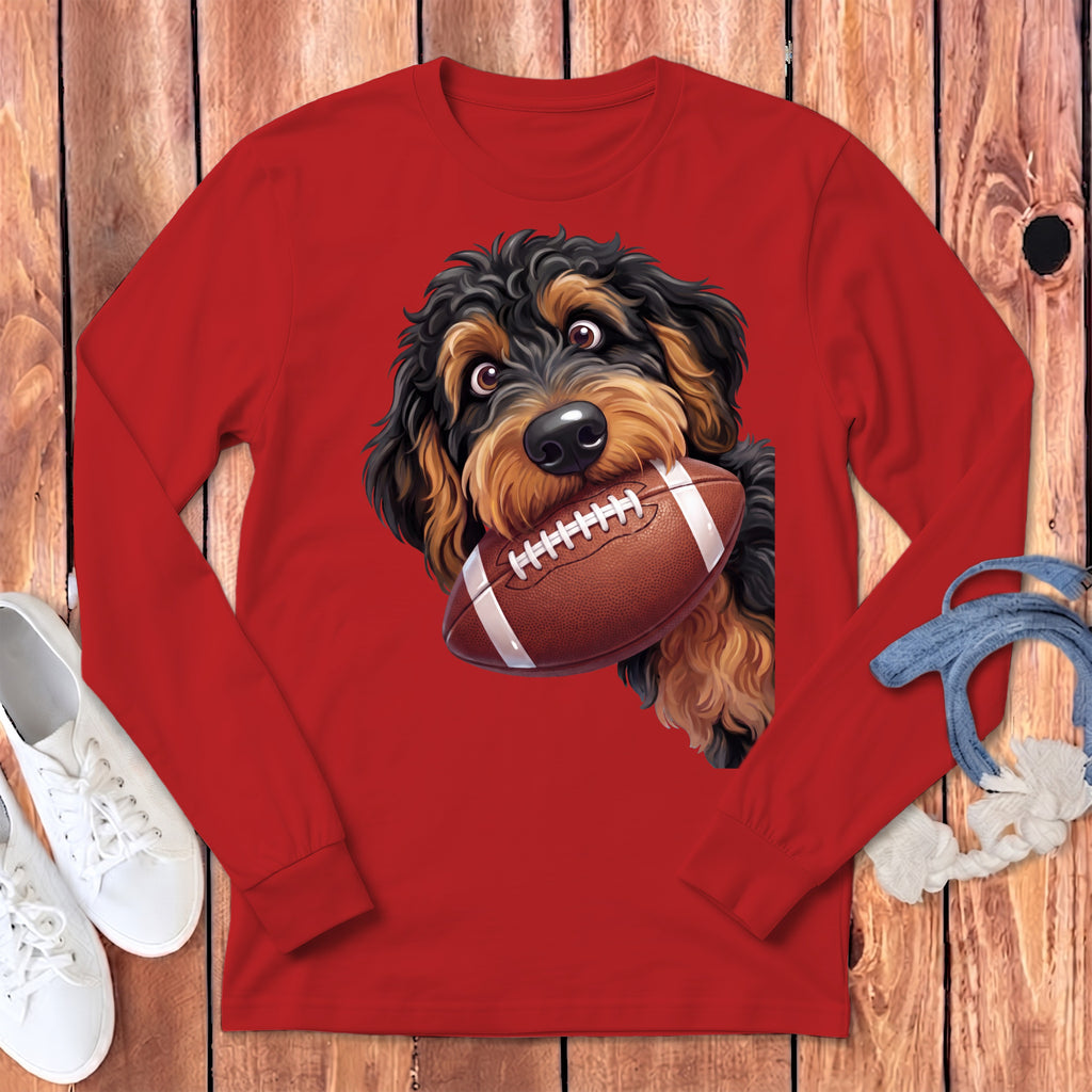 Fluffy dog with a football in its mouth, shown on a red long-sleeved shirt.