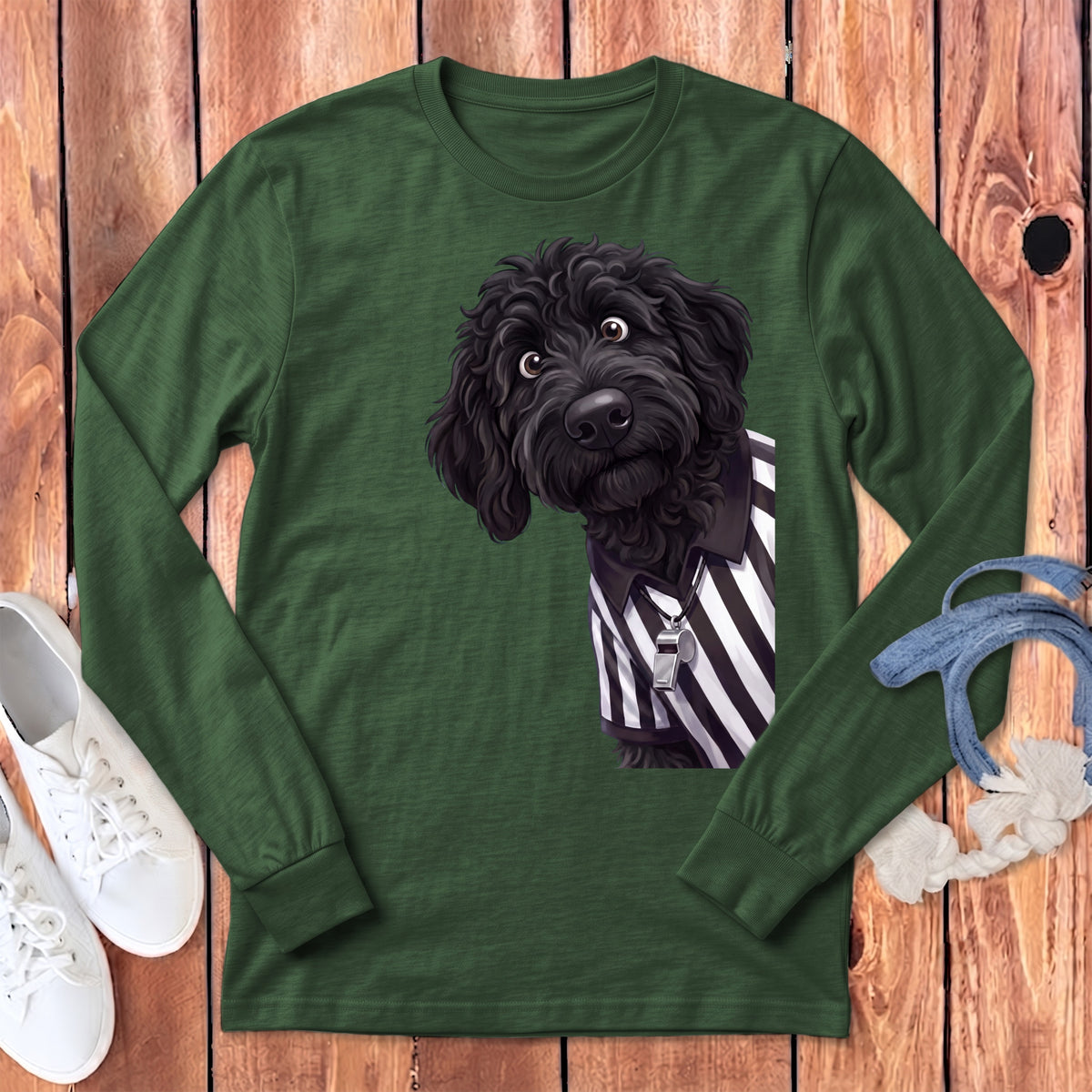 Black poodle wearing a referee shirt and whistle graphic on a green long-sleeve shirt.