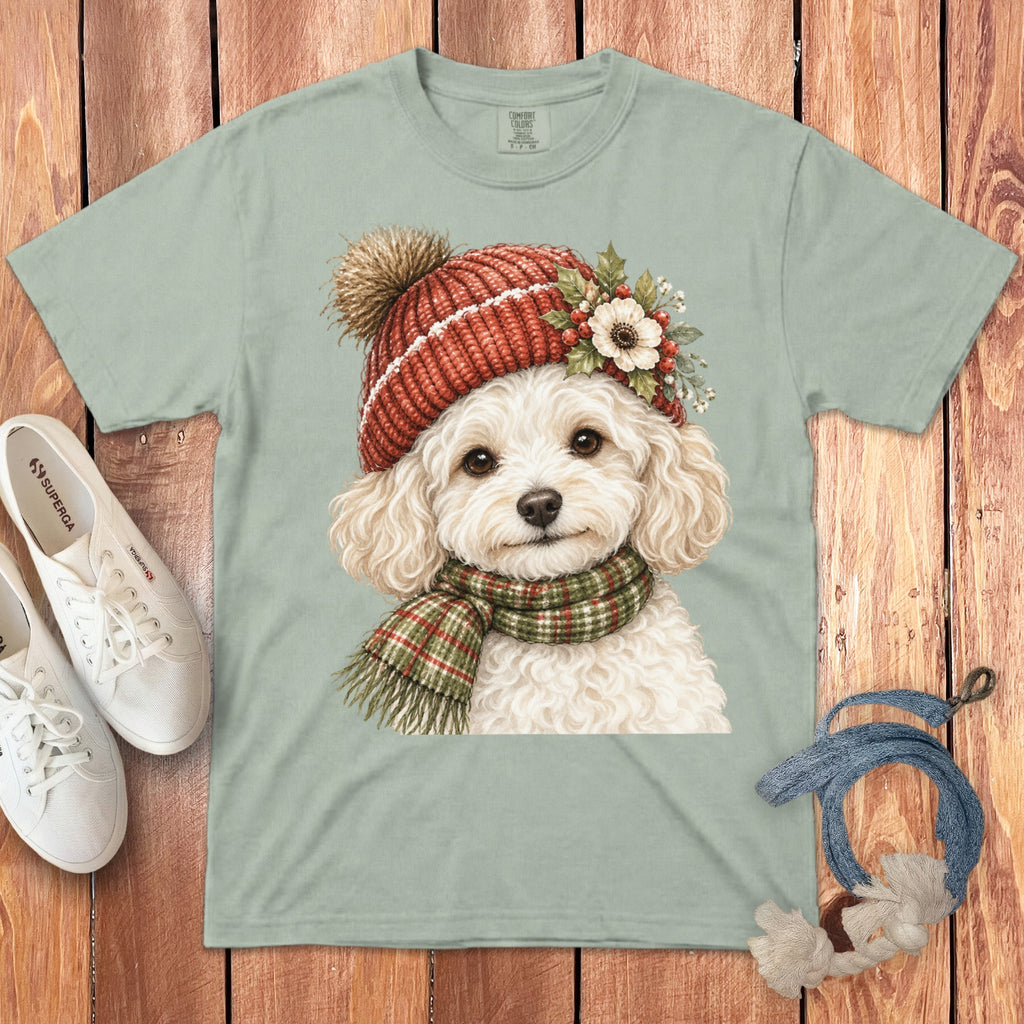 Light green t-shirt with watercolor illustration of a white poodle wearing a red knit hat and scarf.