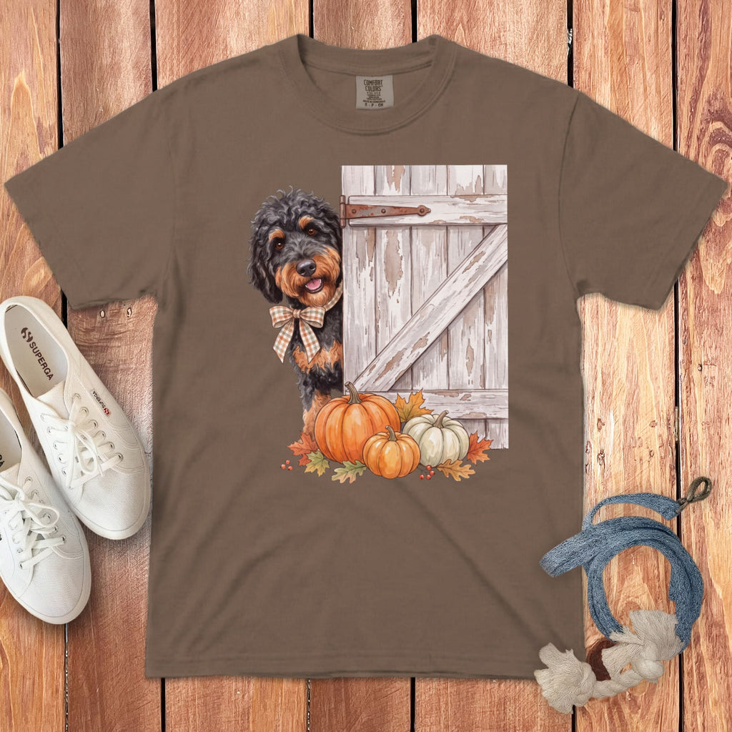 Brown t-shirt with a watercolor doodle dog peeking from behind a rustic barn door with pumpkins.