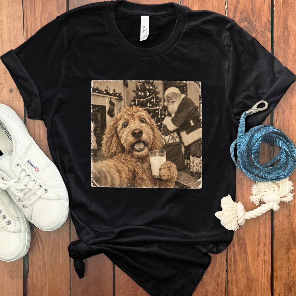 A black t-shirt featuring a vintage graphic of a doodle dog holding a glass of milk with Santa Claus in the background.