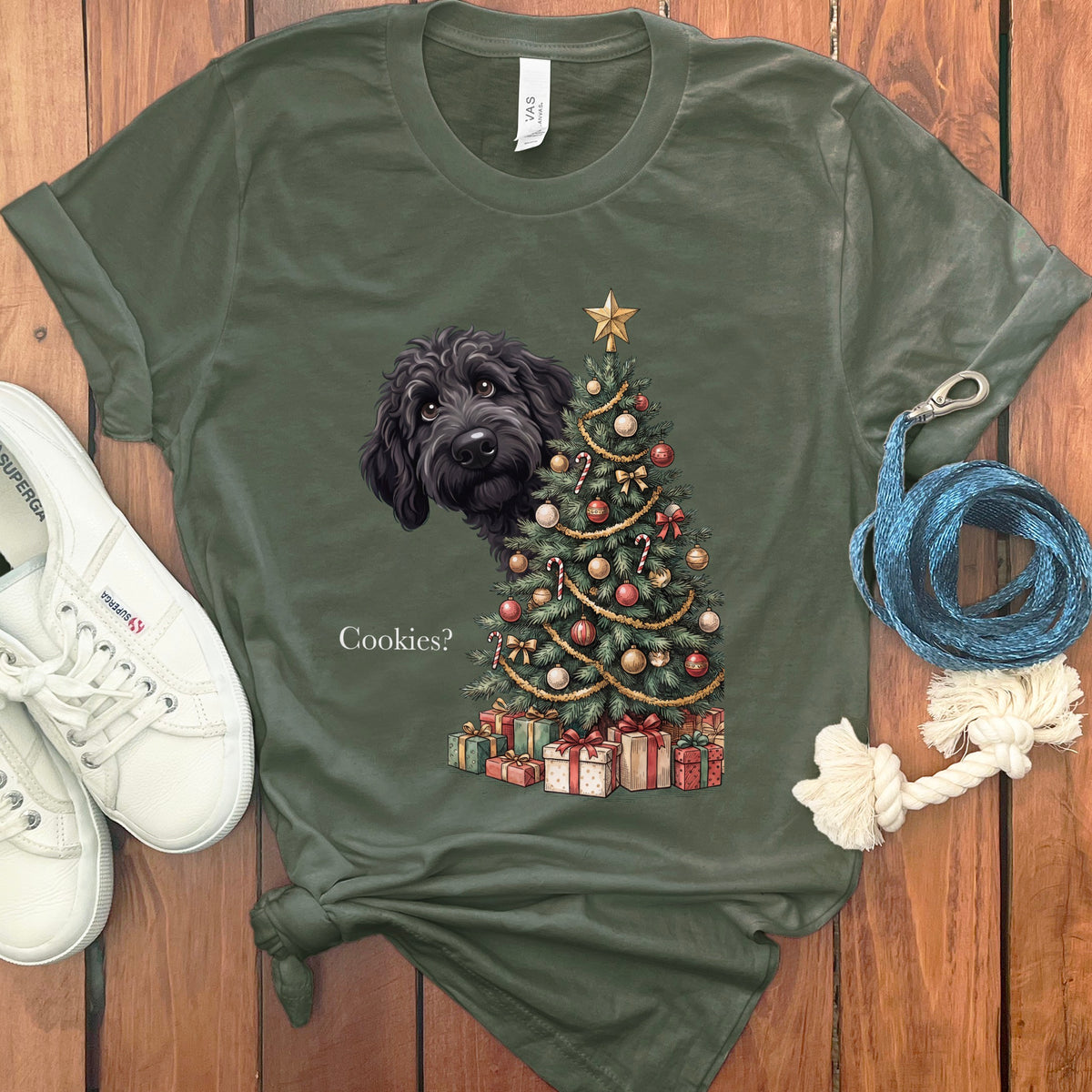 T-shirt with a black dog peeking behind a decorated Christmas tree and gifts.