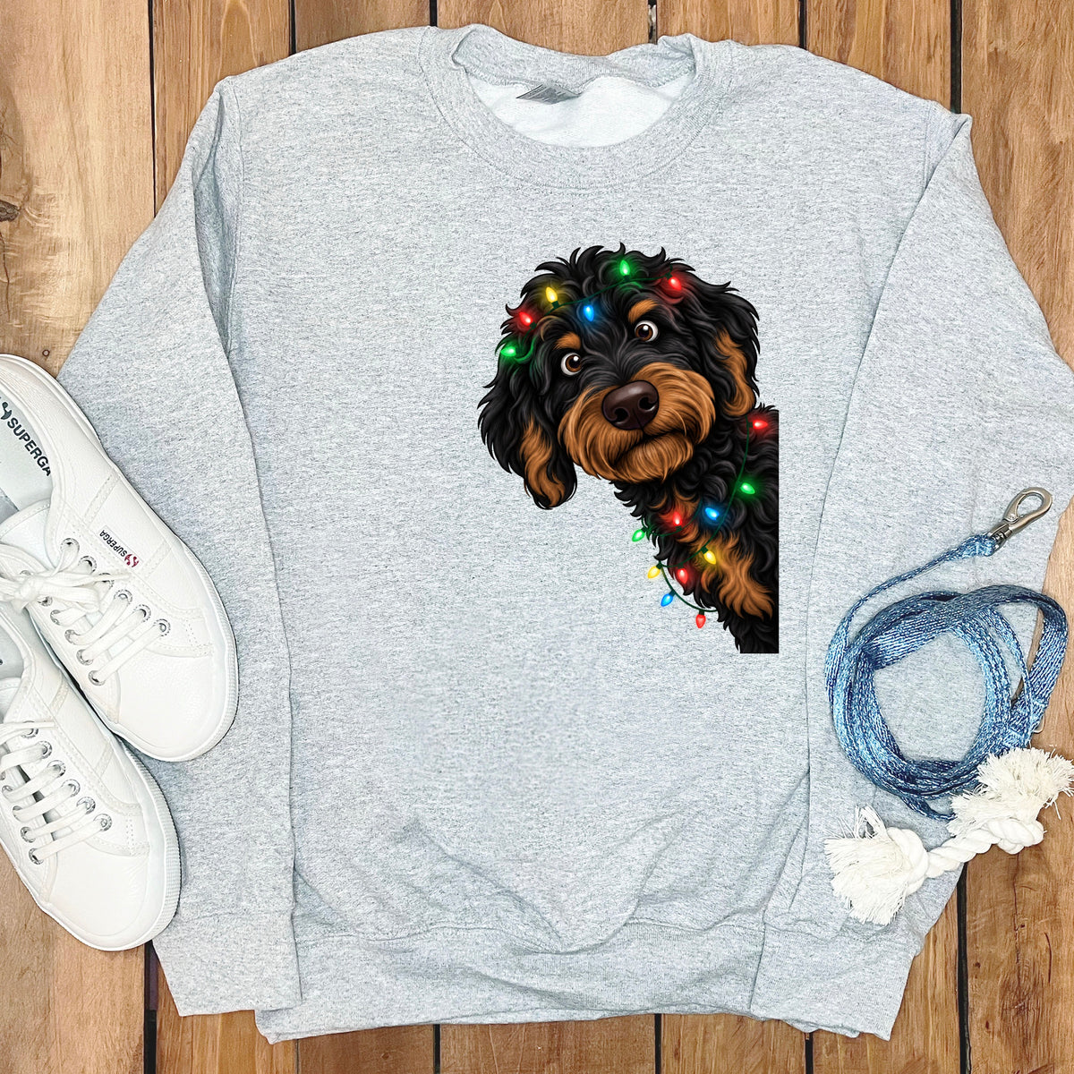 Grey sweatshirt with a cartoon dog wearing colorful Christmas lights.