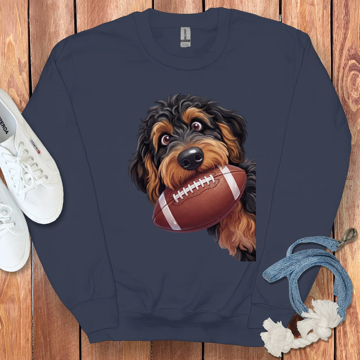 Navy sweatshirt with a dog holding a football on dark wooden background.