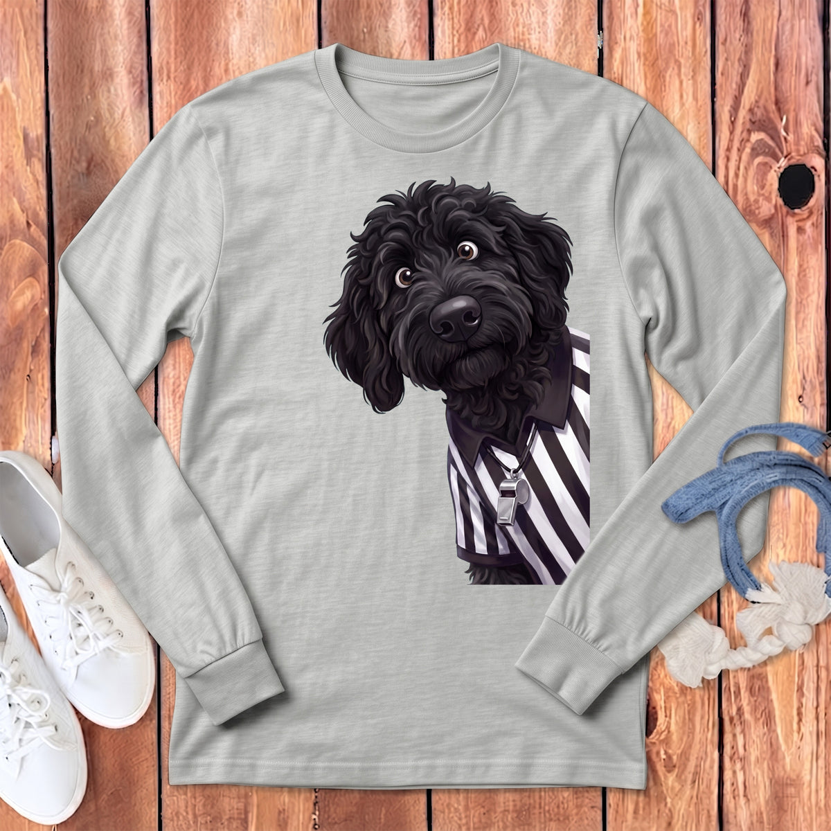 Black doodle dog wearing a referee shirt and whistle on a light grey long-sleeved shirt.