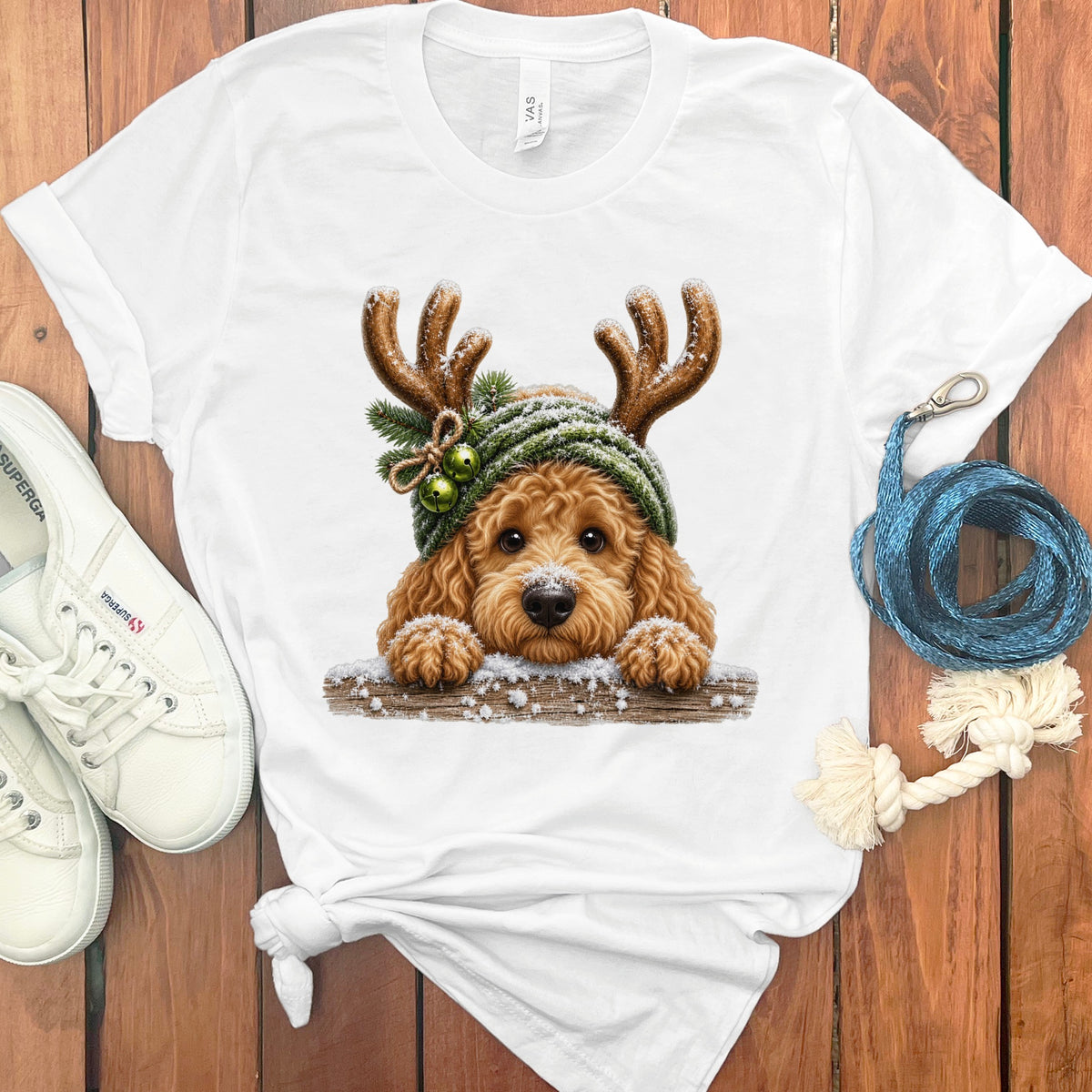 Goldendoodle wearing a green Santa hat with reindeer antlers, snow, and bells.