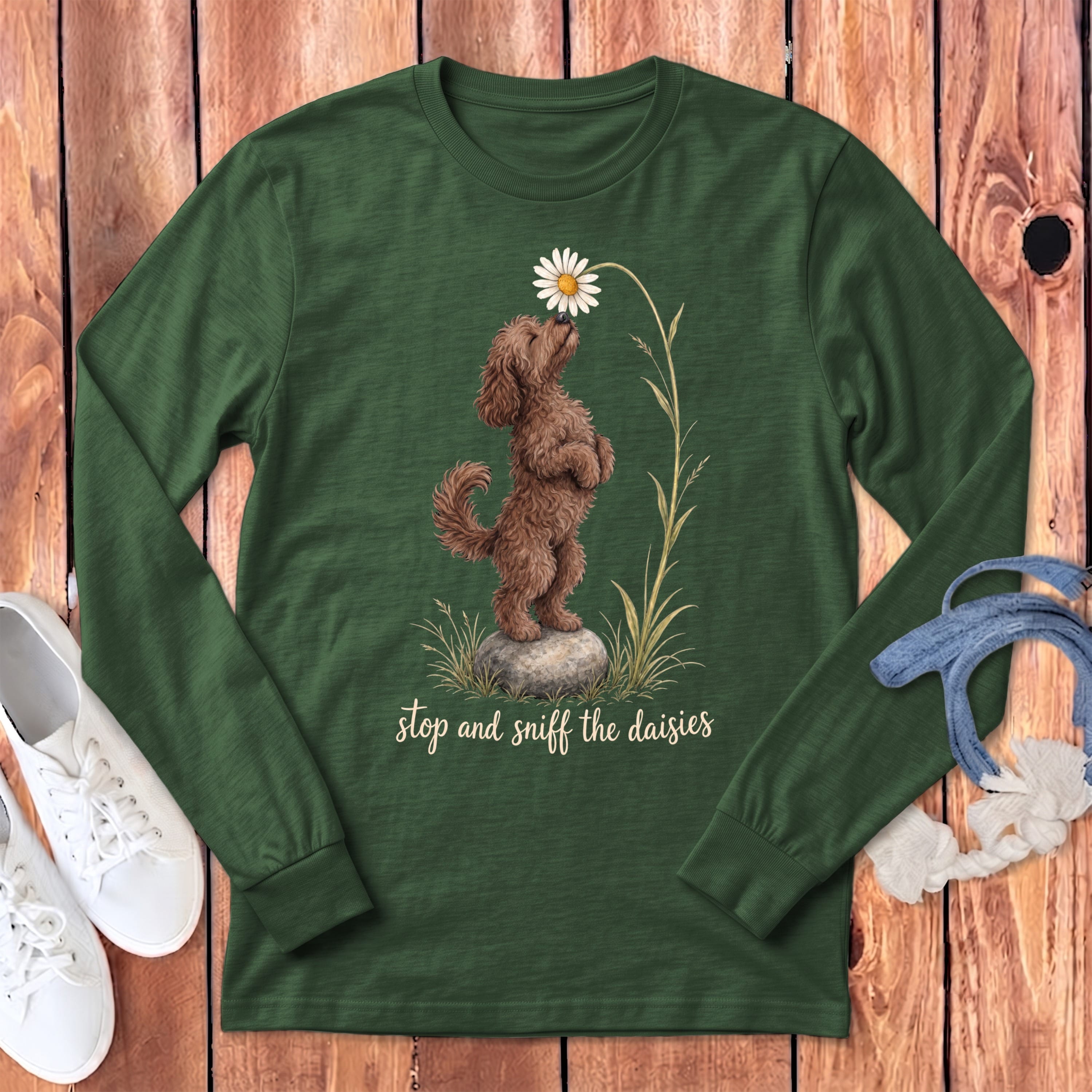 Green long-sleeve shirt with brown dog smelling a daisy, text reads "stop and sniff the daisies".
