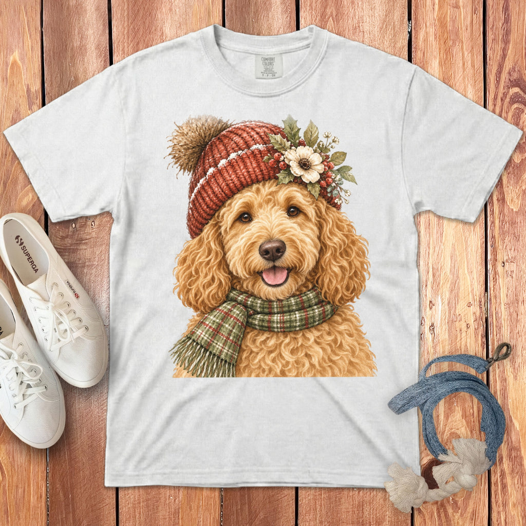 White t-shirt with a watercolor print of a goldendoodle wearing a red knitted hat and scarf.