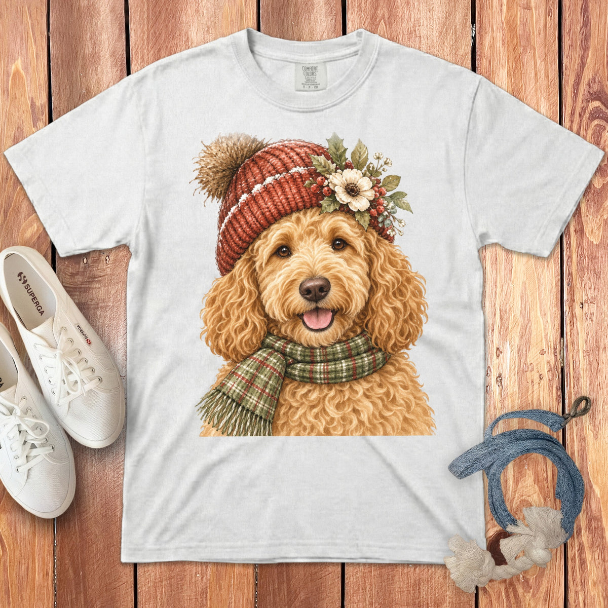 White t-shirt with a watercolor print of a goldendoodle wearing a red knitted hat and scarf.
