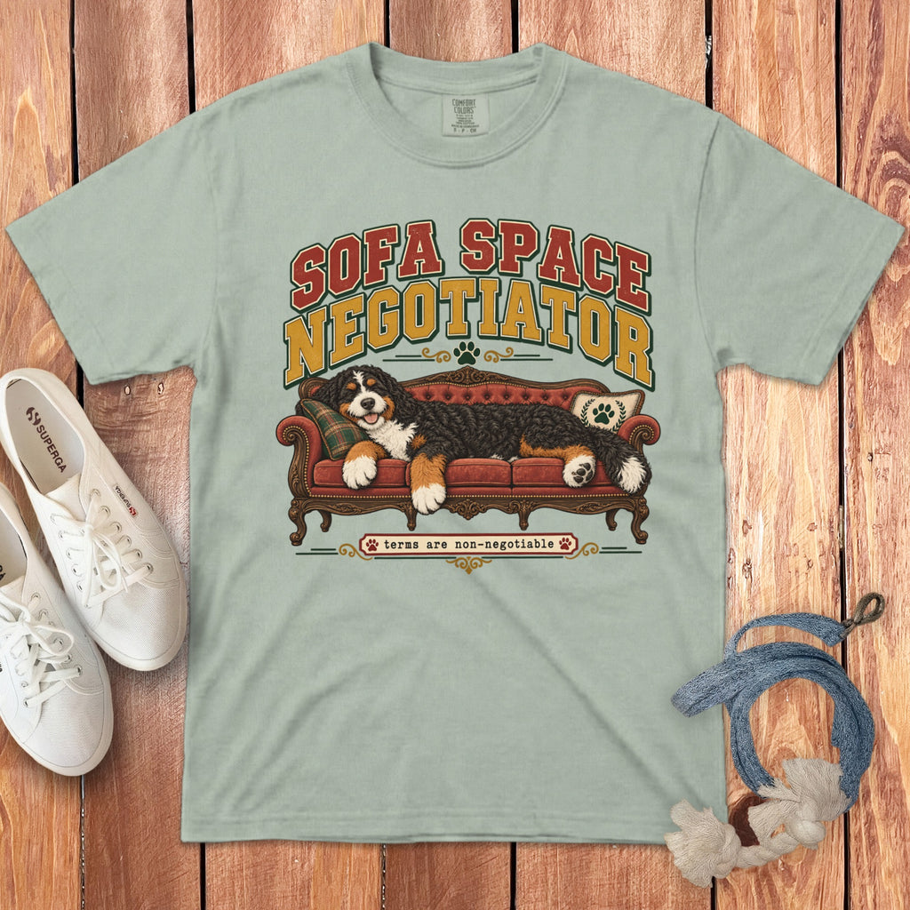 Light green t-shirt with a graphic of a Bernese Mountain Dog on a red sofa, white sneakers, and a rope on a wooden background.