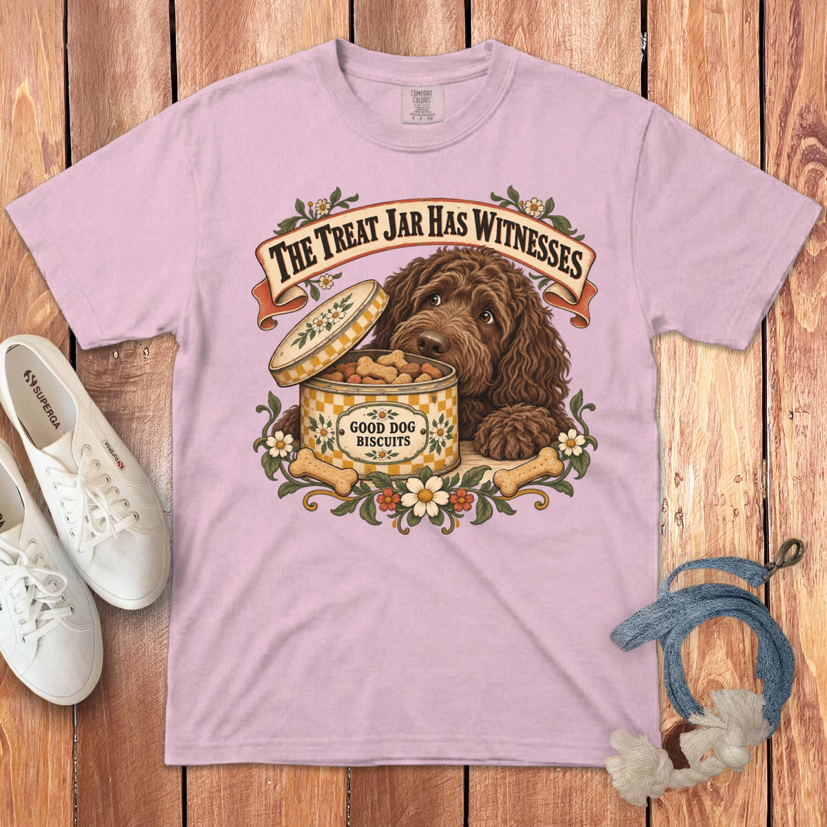 A light pink t-shirt featuring a graphic of a brown dog beside an open biscuit tin.
