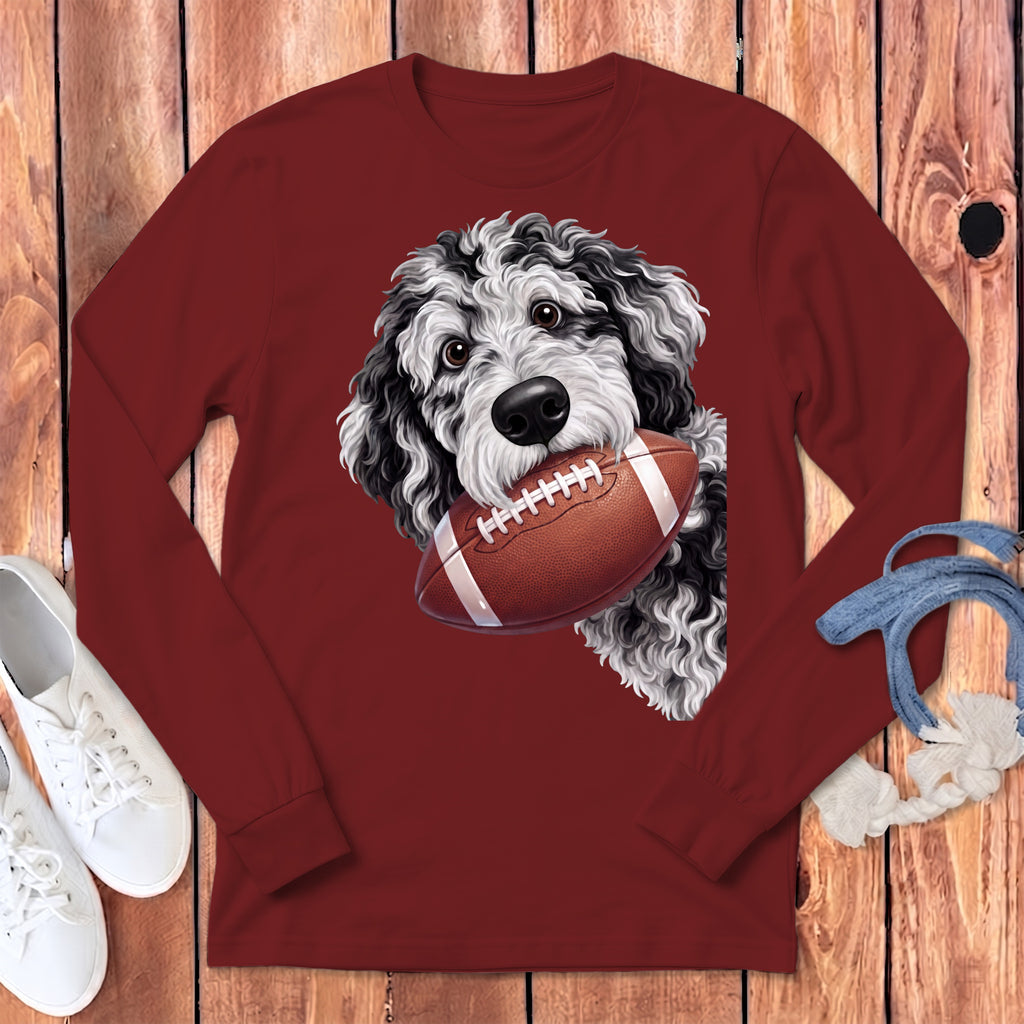 A maroon long-sleeve t-shirt with a graphic of a black and white dog holding a football.