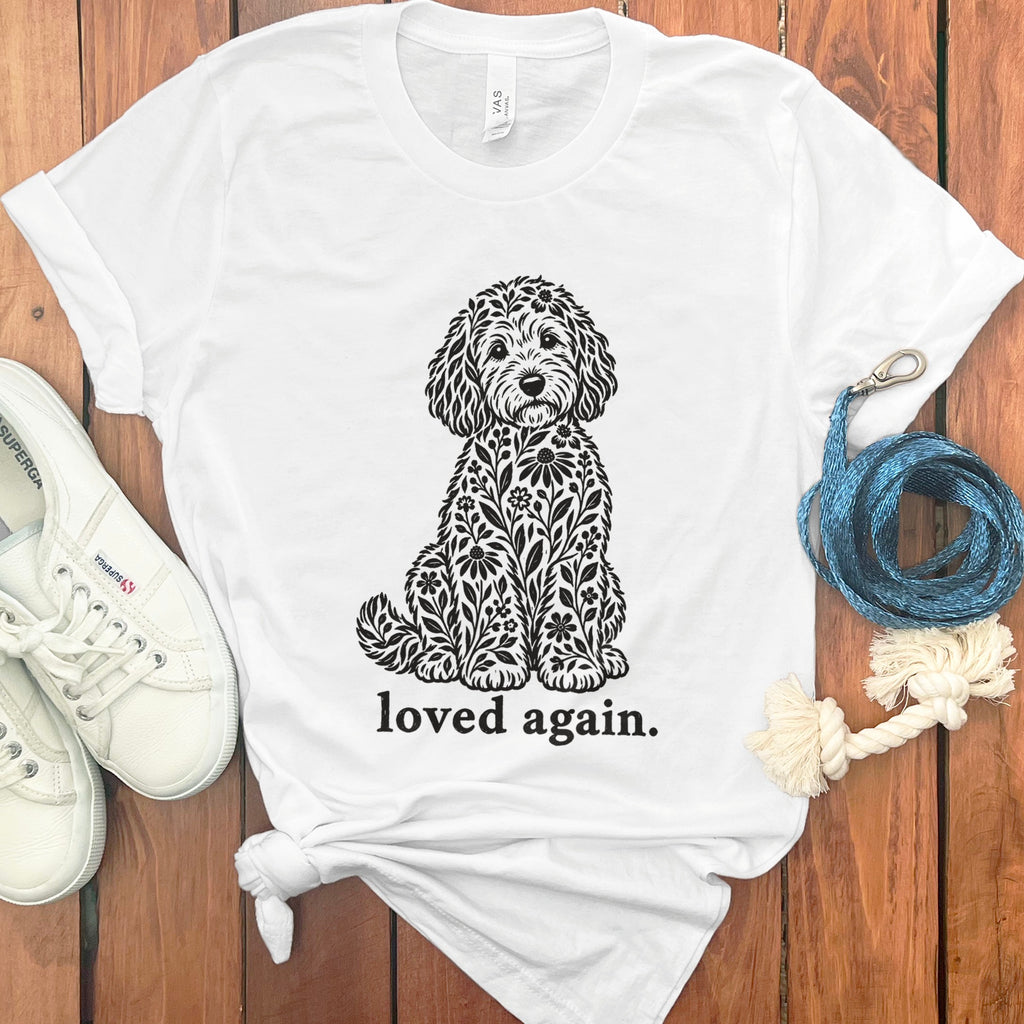 White t-shirt with black floral dog graphic and text "loved again."