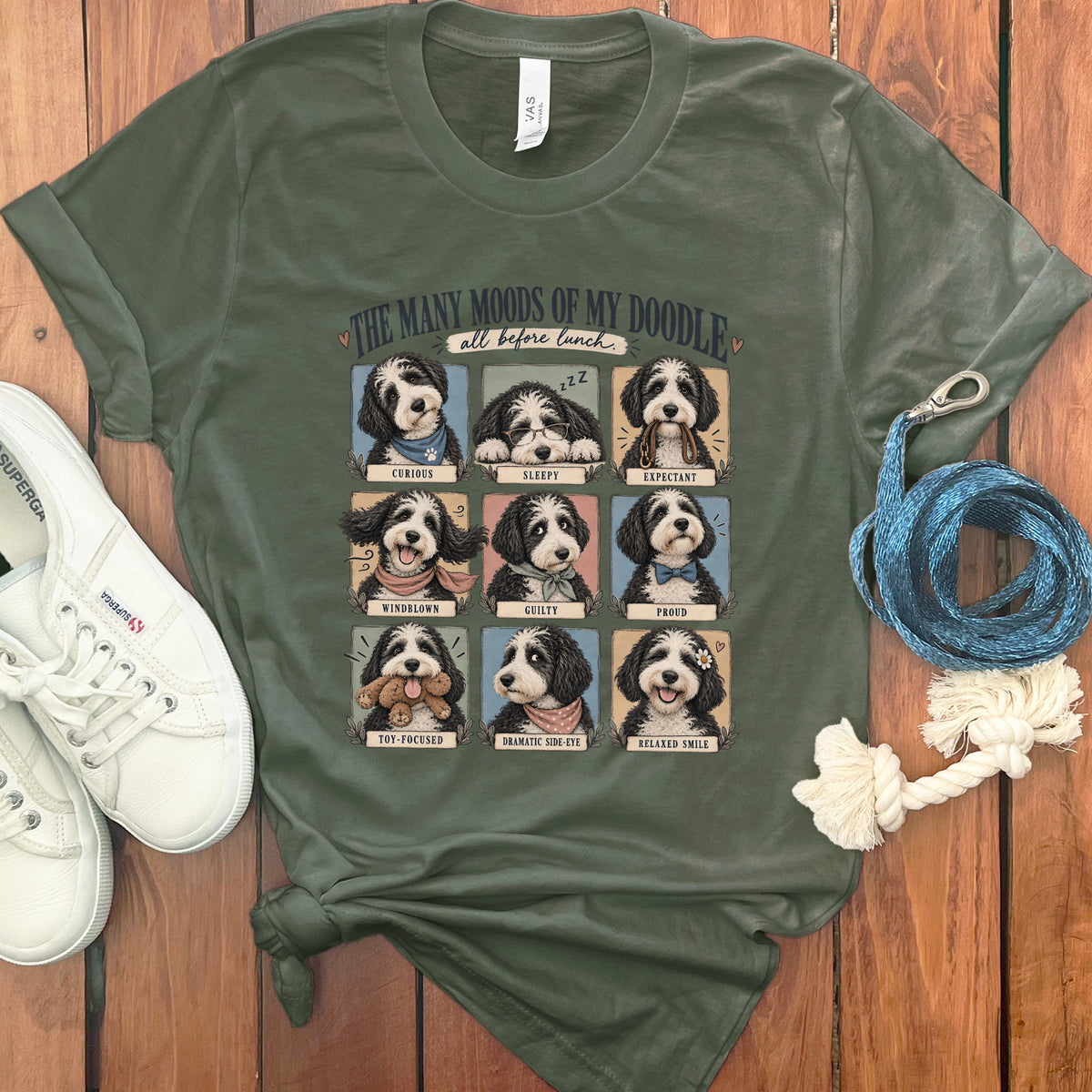 Green t-shirt with nine panels of doodles depicting various moods: curious, sleepy, expectant, windblown, guilty, proud, toy-focused, dramatic side-eye, and relaxed smile.