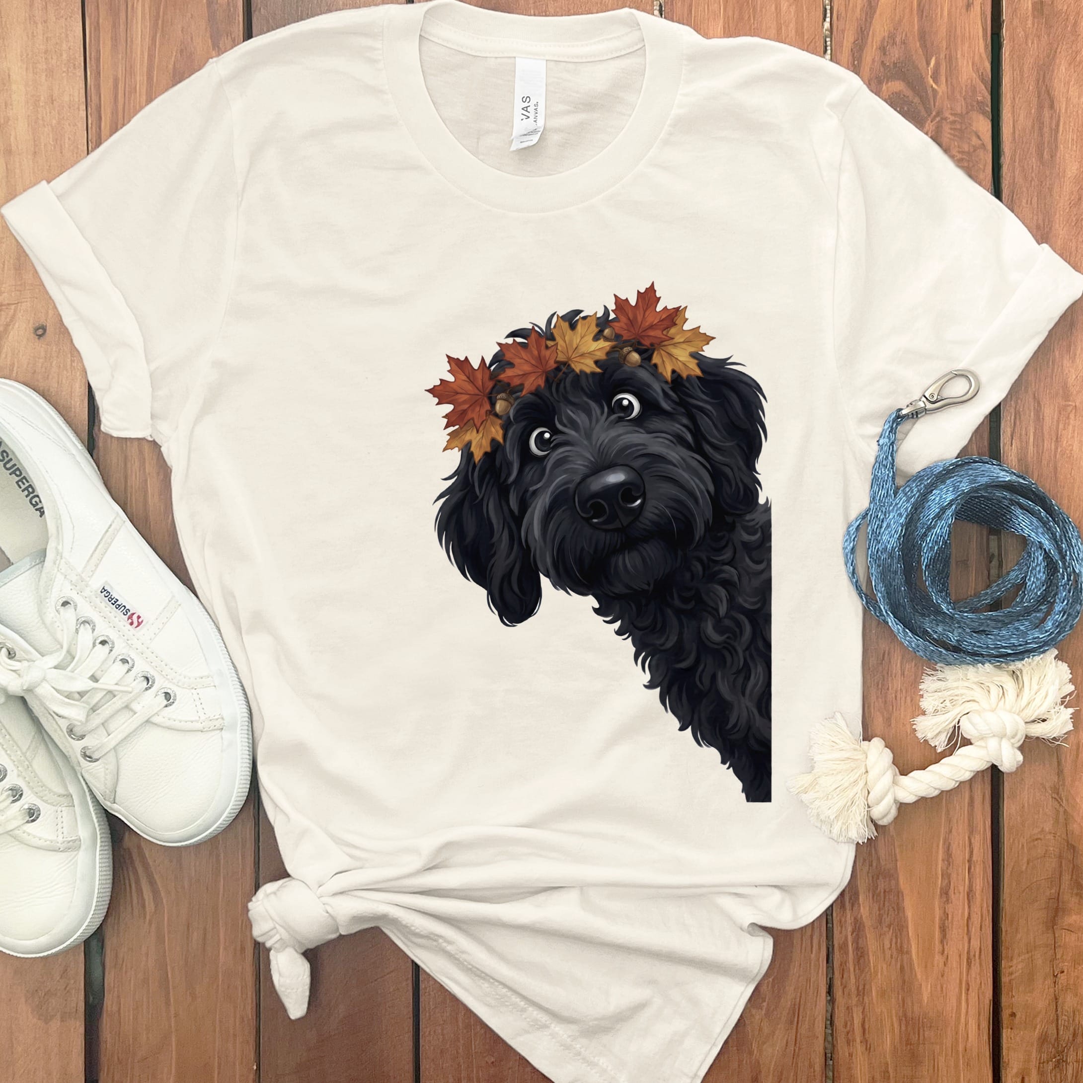 Black dog with autumn leaf crown on a cream t-shirt.