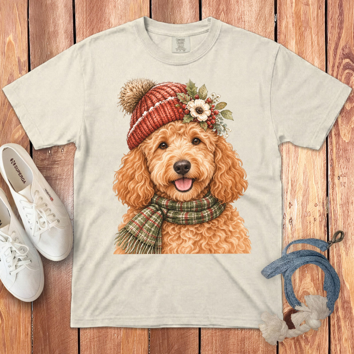 Cream t-shirt with watercolor print of a happy dog wearing a Santa hat and scarf.